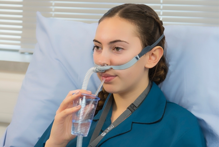 Patientin mit Nasensonde trinkt aus einem Becher