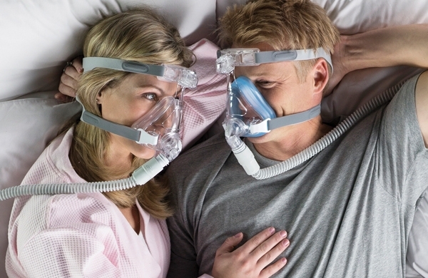 Ein Paar liegt kuschelnd im Bett, beide tragen eine Amara Gel Maske