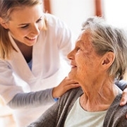Pflegerin betreut ältere Patientin und legt ihr die Hand auf die Schulter