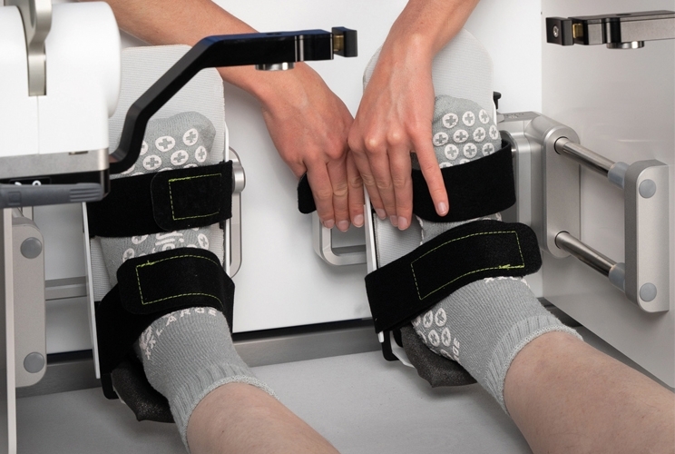 Patientenfüße in Socken werden für die Frühmobilisierung mit Schlaufen am Vemotion System fixiert