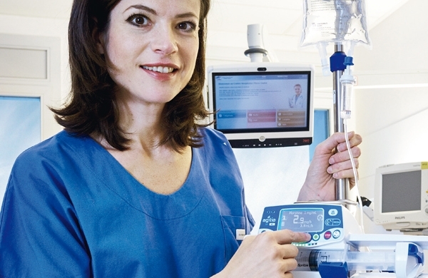 Eine Pflegerin tippt auf eine Taste unter dem großen Display der Agilia SP PCA WiFi