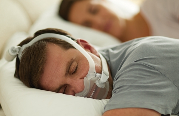 Paar schläft im Bett, Mann liegt auf seinem Bauch und trägt die DreamWear Full Face Maske