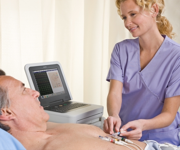 Lächelnde Pflegerin legt Elektroden bei Patienten an