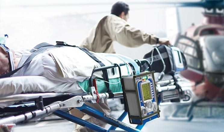 Patient wird im Krankenbett zum Helikopterlandeplatz geschoben und wird dabei mit ZVent beatmet